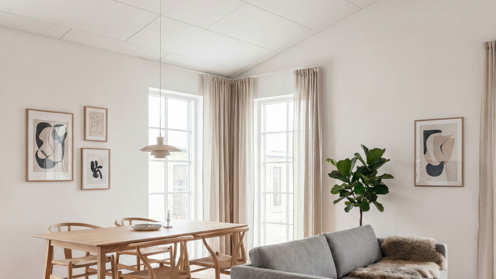Akustikloft i stue med spisebord, sofa og store vinduer, hvor loftpaneler forbedrer lyd og indeklima
